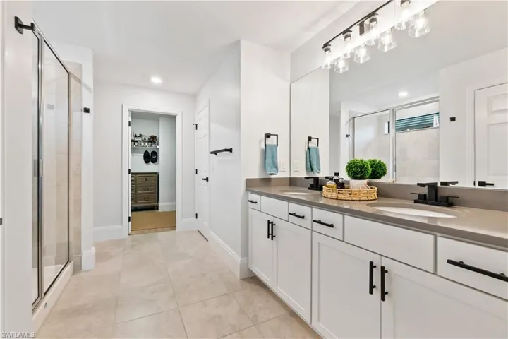 Full bath featuring a stall shower, double vanity, recessed lighting, and tile patterned floors