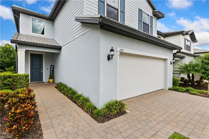 View of exterior entry featuring a garage, stucco siding, and driveway