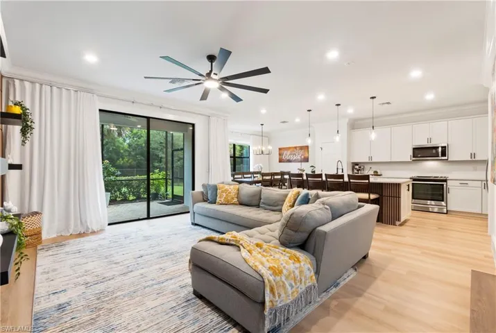 Living room with crown molding, a ceiling fan, light wood-style floors, and recessed lighting