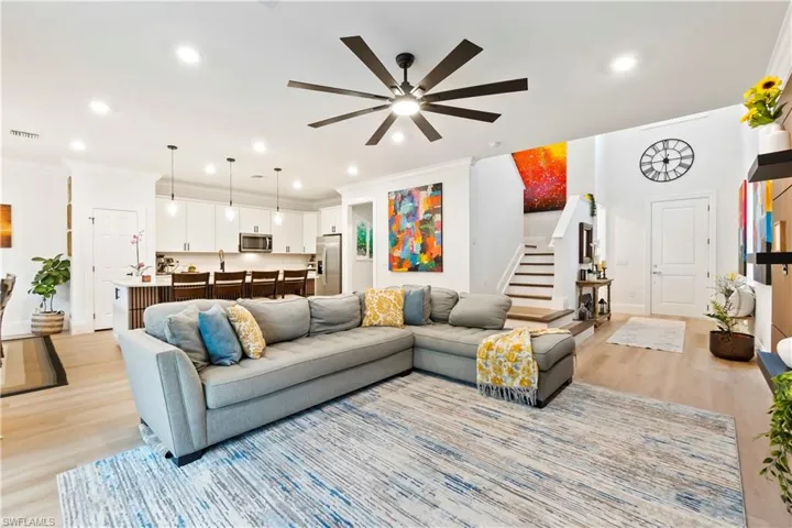 Living room featuring a ceiling fan, stairway, crown molding, light wood-type flooring, and recessed lighting