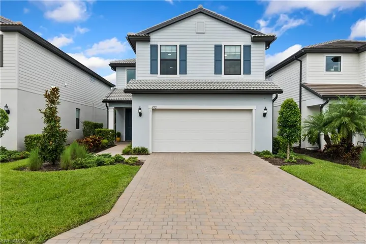 View of front facade with an attached garage, a tile roof, driveway, and a front yard