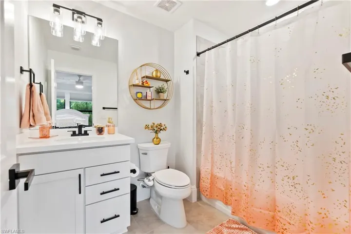 Full bath with vanity, tile patterned flooring, curtained shower, and a ceiling fan