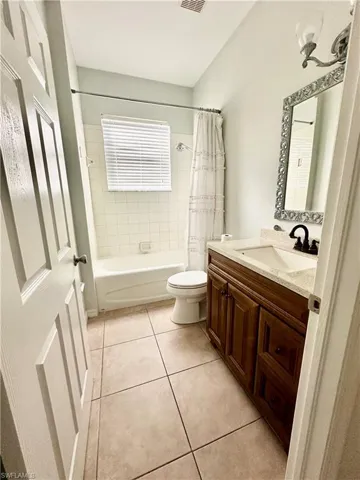 Full bathroom featuring vanity, tile patterned flooring, shower / bathtub combination with curtain, and toilet