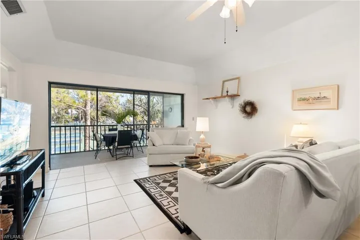 Living room featuring a tray ceiling, ceiling fan, and light tile patterned flooring