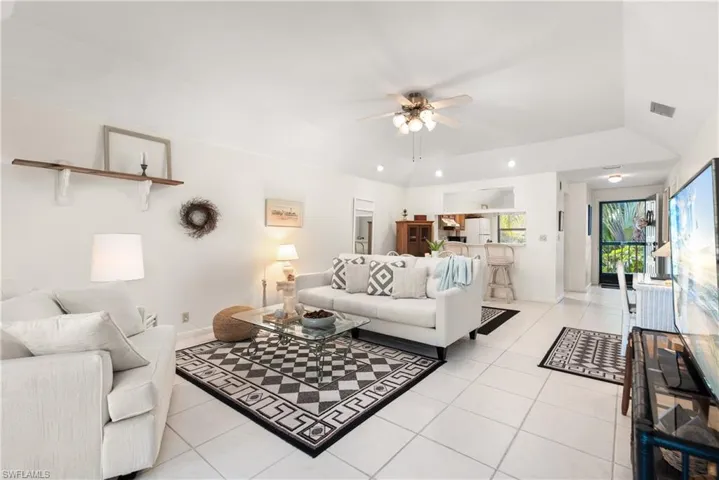 Living room featuring ceiling fan, light tile patterned flooring, and lofted ceiling