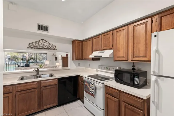 Kitchen featuring black appliances, light tile patterned floors, and sink
