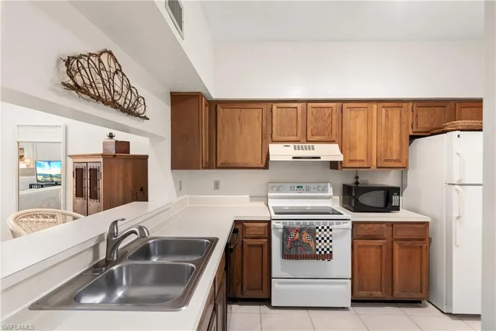Kitchen with sink, light tile patterned floors, and white appliances