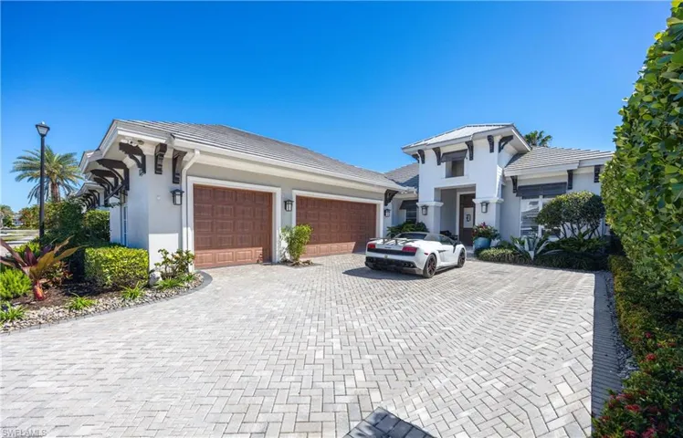 View of front of property with decorative driveway, a garage, and stucco siding