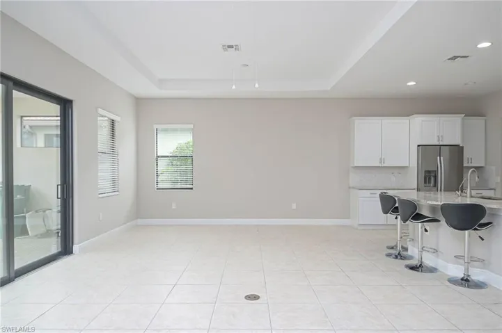 Kitchen featuring white cabinetry, a tray ceiling, stainless steel fridge with ice dispenser, and a breakfast bar