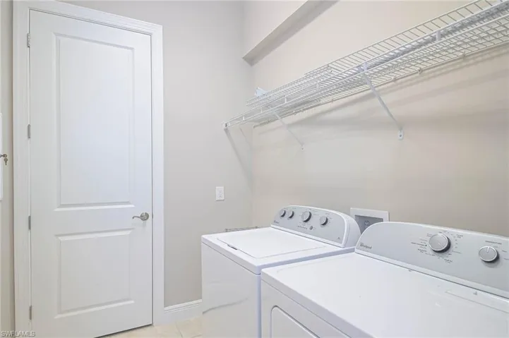 Clothes washing area featuring light tile patterned flooring and independent washer and dryer