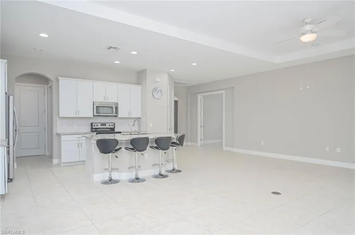 Kitchen with stainless steel appliances, sink, a breakfast bar area, an island with sink, and white cabinets