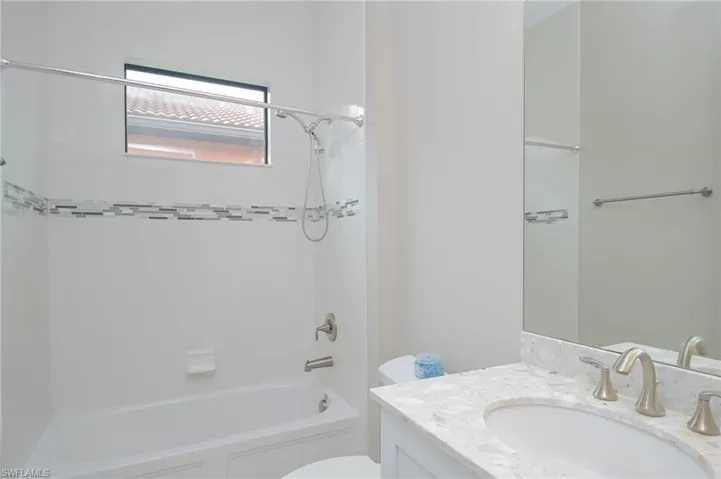 Full bathroom featuring toilet, vanity, and tiled shower / bath