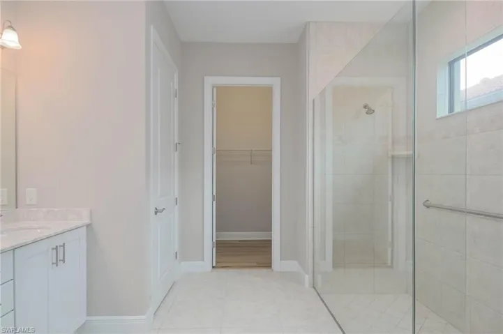Bathroom featuring walk in shower, vanity, and tile patterned floors