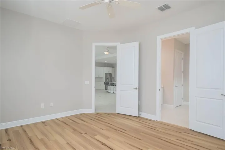 Unfurnished bedroom featuring stainless steel fridge, ceiling fan, and light hardwood / wood-style flooring