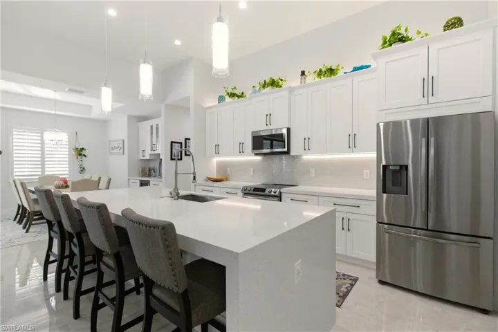 Kitchen featuring appliances with stainless steel finishes, white cabinetry, hanging light fixtures, a kitchen breakfast bar, and recessed lighting