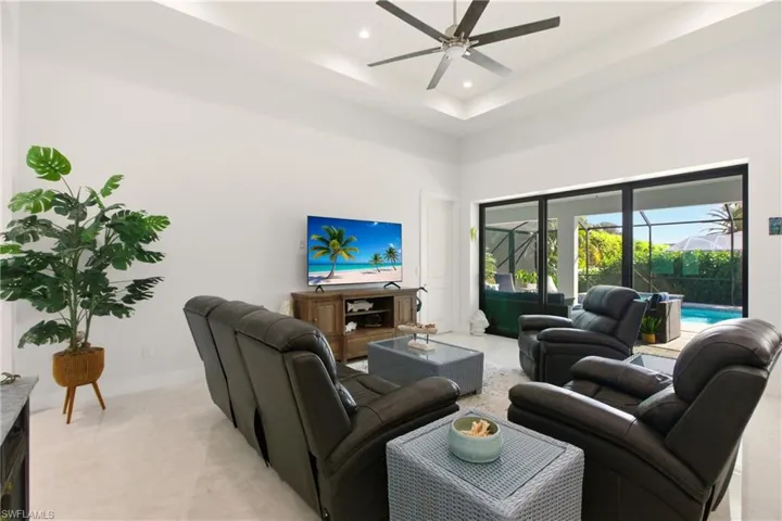 Living area with a towering ceiling, recessed lighting, a tray ceiling, a ceiling fan, and a sunroom