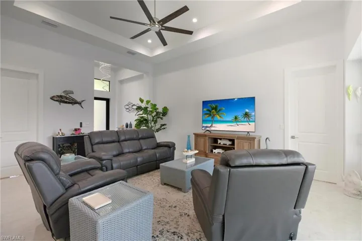 Living area with a raised ceiling, recessed lighting, a high ceiling, and a ceiling fan