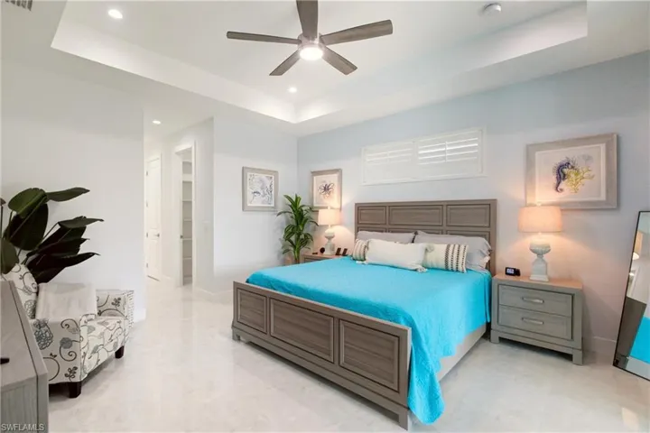 Bedroom featuring a tray ceiling, ceiling fan, a walk in closet, and recessed lighting