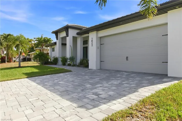View of front of home featuring stucco siding, a front yard, and decorative driveway