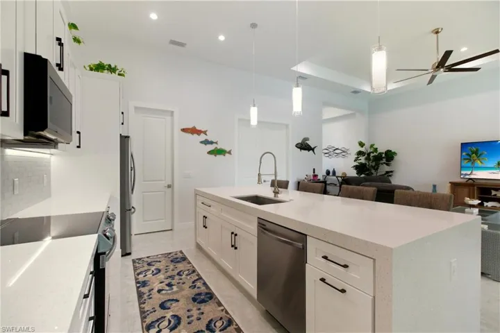 Kitchen with white cabinets, stainless steel appliances, hanging light fixtures, light stone counters, and recessed lighting