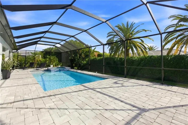 View of swimming pool with a sunroom, a pool with connected hot tub, glass enclosure, and a patio