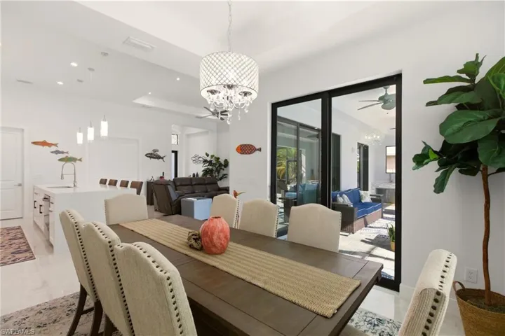Dining space with a raised ceiling, recessed lighting, a chandelier, and a ceiling fan