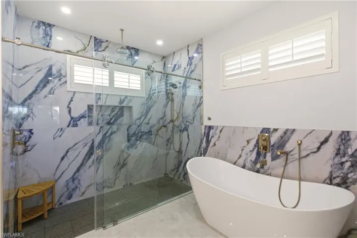 Full bathroom with a soaking tub, a marble finish shower, recessed lighting, marble tiled floors, and tile walls