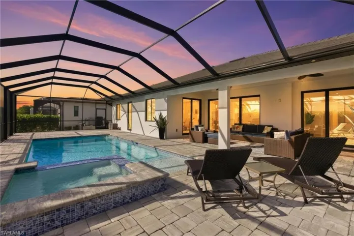 View of pool with a pool with connected hot tub, a sunroom, glass enclosure, an outdoor living space, and a patio