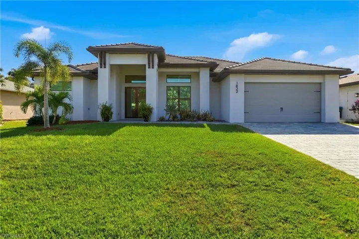 Prairie-style home with a tiled roof, a front lawn, and stucco siding