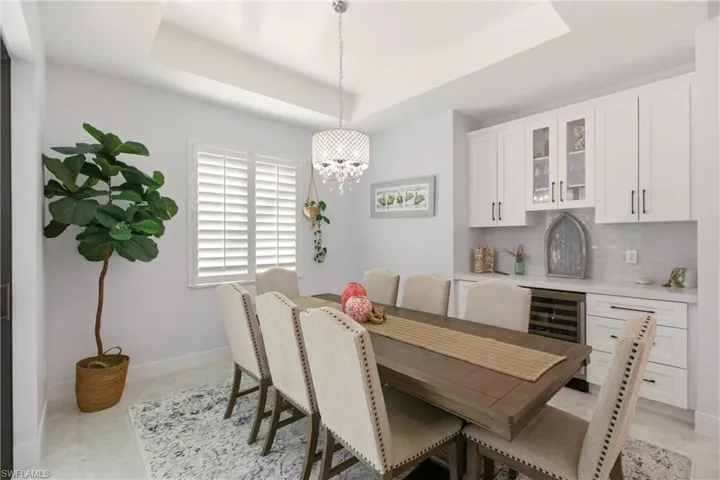 Dining area with beverage cooler, a chandelier, and a raised ceiling