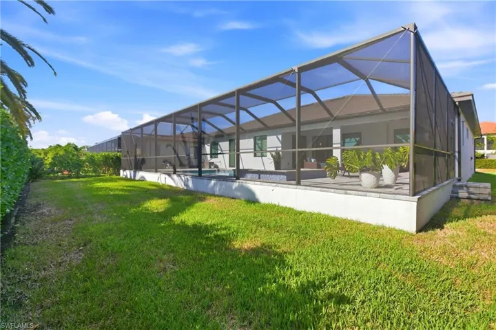 Rear view of house featuring a sunroom, glass enclosure, and a lawn