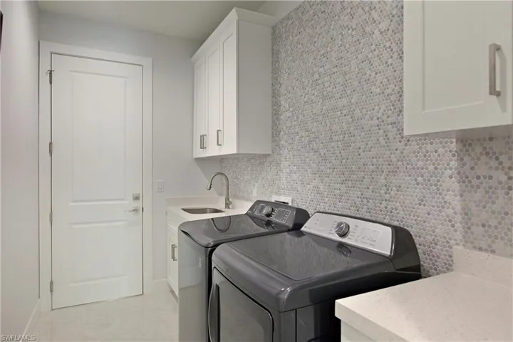 Washroom featuring cabinet space, light tile patterned floors, and washer and dryer