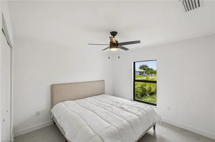 Bright interior space featuring a ceiling fan with integrated lighting, a large window with black trim, and light-toned flooring