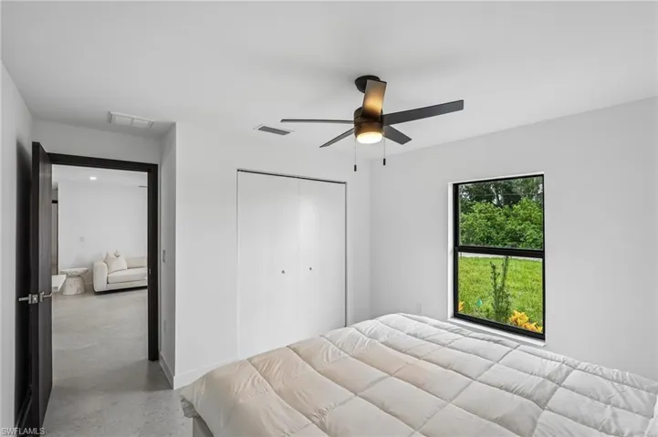 Room featuring a matte black ceiling fan with integrated lighting, a large window with a dark frame, and white bifold closet doors