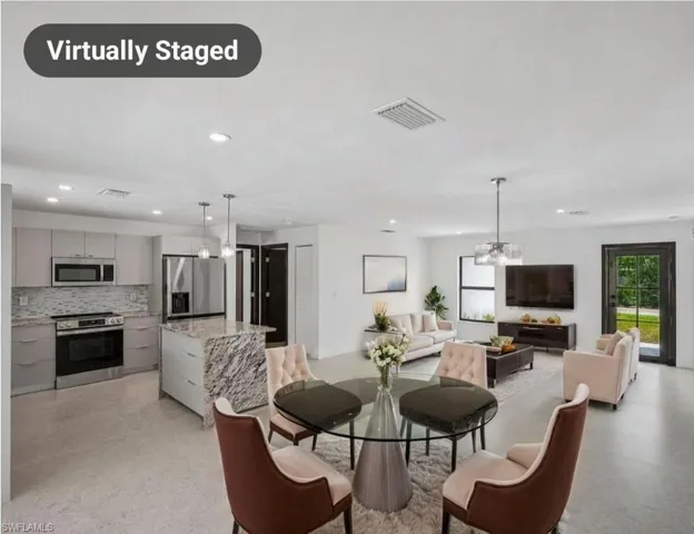 Open-concept living area featuring a modern kitchen with stainless steel appliances, a center island with a stone countertop, recessed lighting, and a glass-paneled exterior door