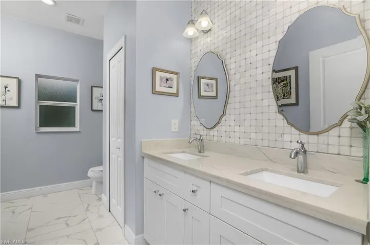 Primary bathroom with tile floors and dual bowl vanity