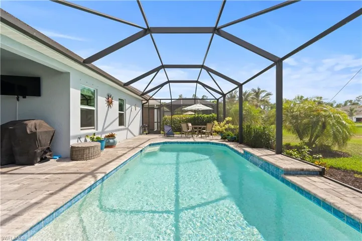 Pool featuring area for grilling, a patio, and glass enclosure