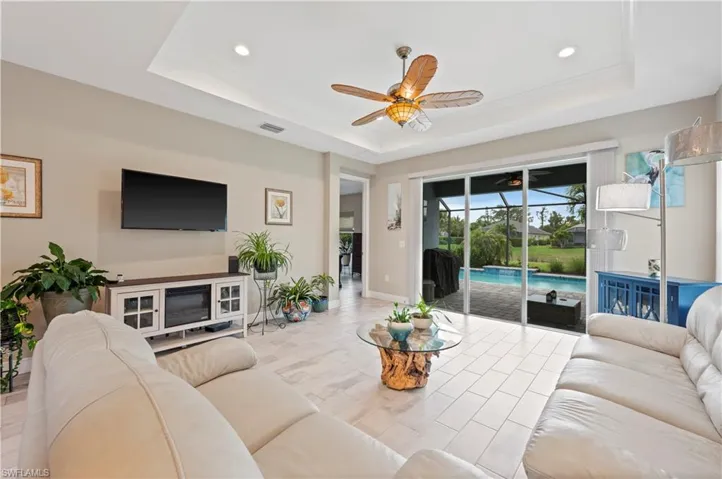Living room with visible vents, a raised ceiling, and a ceiling fan