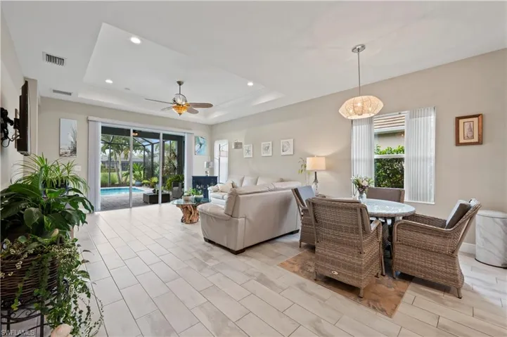 Living area featuring visible vents, ceiling fan, a raised ceiling, and plenty of natural light