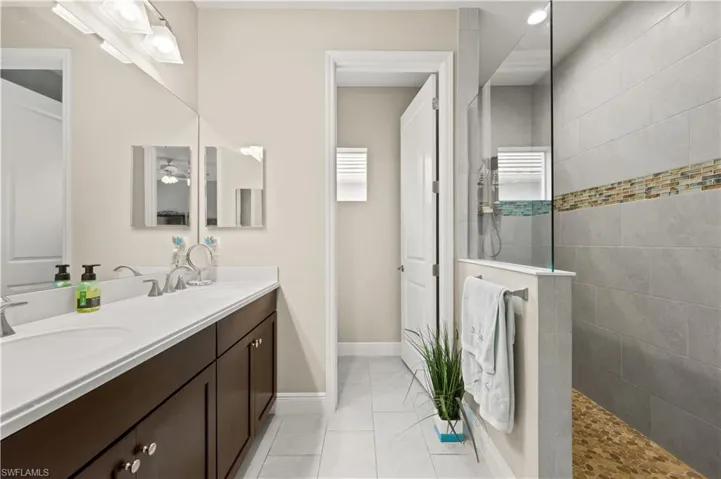Full bathroom featuring a sink, walk in shower, double vanity, and tile patterned flooring