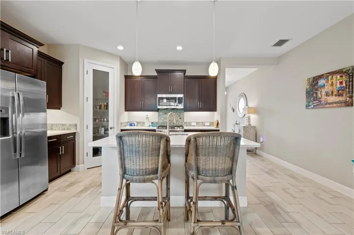 Kitchen featuring appliances with stainless steel finishes, decorative backsplash, light countertops, and wood tiled floor