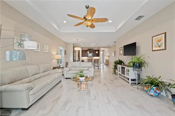 Living area with recessed lighting, a raised ceiling, light wood-style flooring, visible vents, and ceiling fan