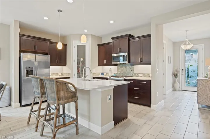 Kitchen with stainless steel appliances, dark brown cabinetry, a sink, and decorative backsplash