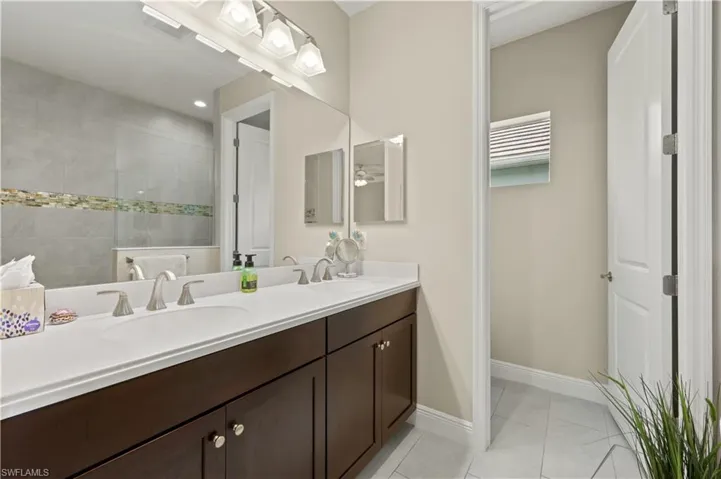 Full bathroom featuring tile patterned flooring, double vanity, baseboards, and a sink