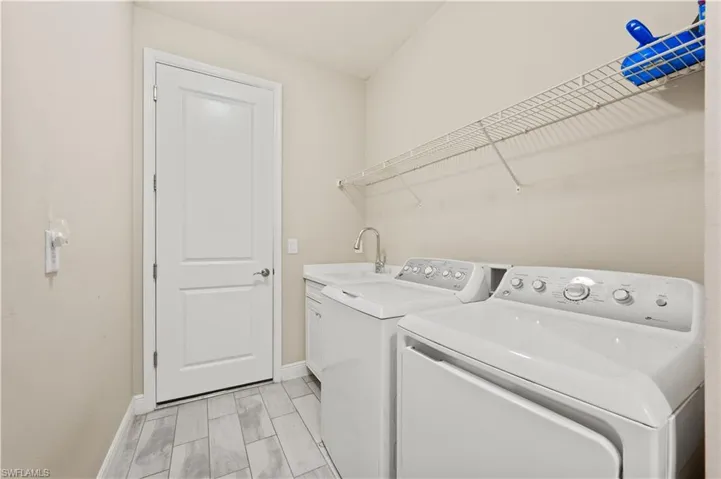Washroom featuring a sink, washer and clothes dryer, cabinet space, and baseboards