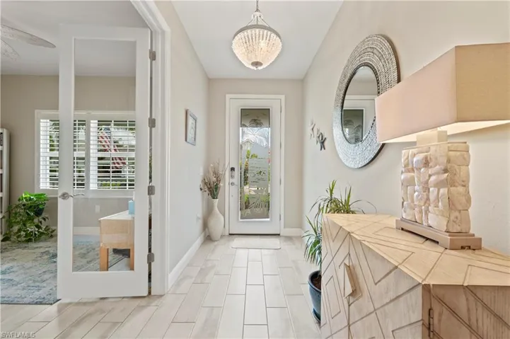 Entryway with an inviting chandelier, baseboards, and wood finish floors