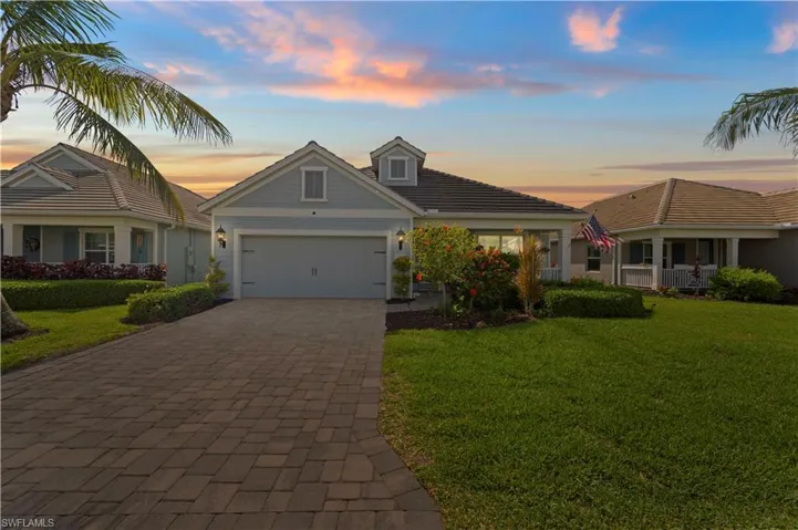View of front of property with an attached garage, decorative driveway, a front lawn, and a tile roof