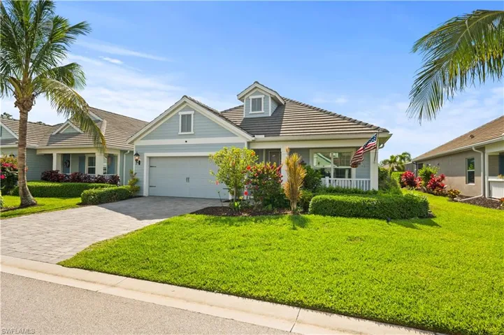 View of front of home featuring an attached garage, decorative driveway, a front lawn, and a tile roof