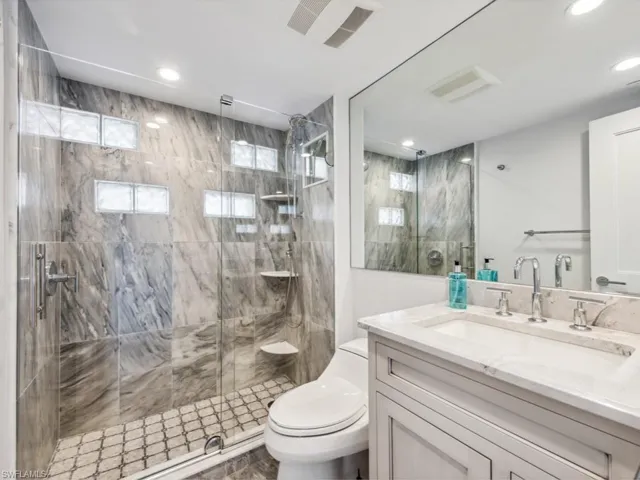 Bathroom featuring a shower door, vanity, and toilet