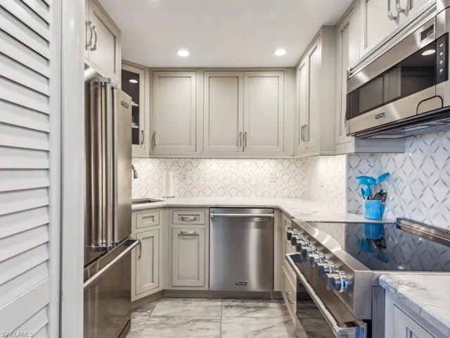 Kitchen with premium appliances, light stone counters, tasteful backsplash, and sink
